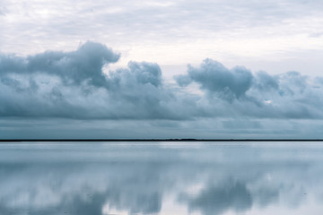 Reflection of sky and clouds with a strip of land in the middle in Iceland