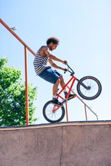 Young man jumping with his BMX bike in a skate park.