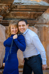 Funny woman holding a man by tie at city. Dominating woman and handsome man. Shot of a cute and sweet woman holding elegant man's tie