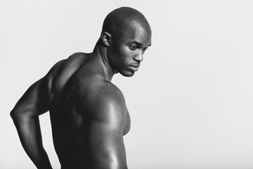 Rear view black and white shot of young man with muscular build looking over shoulder