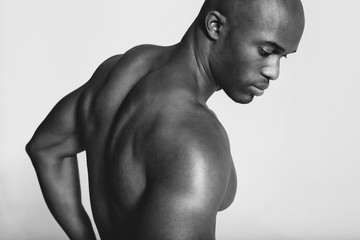 Young african man with muscular build looking down