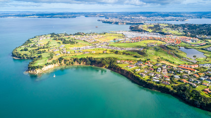 Aerial view on residential suburbs surrounded by sunny ocean harbour. Whangaparoa peninsula, Auckland, New Zealand