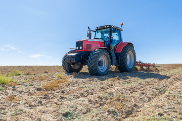Obraz premium agricultural tractor in the foreground with blue sky background.