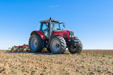 Obraz premium agricultural tractor in the foreground with blue sky background.