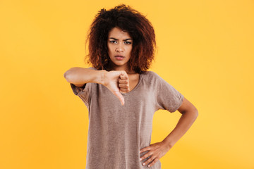 Young angry unhappy woman showing thumb down isolated