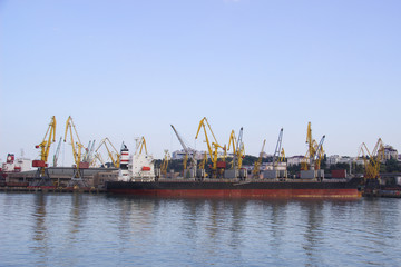 Fototapeta premium Tugboat assisting container cargo ship to harbor quayside.