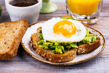 Avocado egg sandwich with whole grain bread on wooden background. Copy space