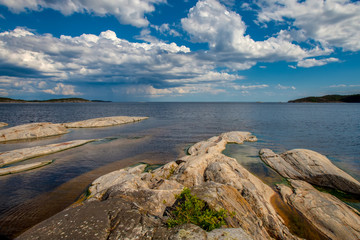 Fototapeta na wymiar Rocks go into the water. Large stones on the shore. Sunny day.