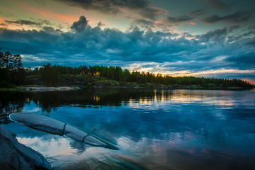 Fototapeta premium The clouds are reflected in the water. Wild nature. Reflection of the sunrise in the water. Karelia. Russia. Ladoga lake.