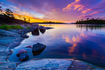 Sunrise over the water. Rocks flooded with sun. Russia. Karelia. Fog over the water. Ladoga lake.