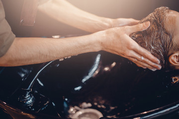 Close-up: a hairdresser washes a client's head for a man