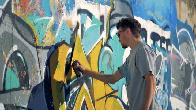 A graffitist refreshes black contours on a wall. 