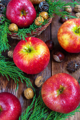 Red apples, fir branches, walnuts, chestnuts and cones on a wooden background, christmas concept, harvest, holiday and new year