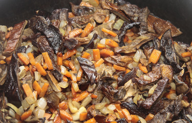Mushrooms fried on the pan with carrot and onion