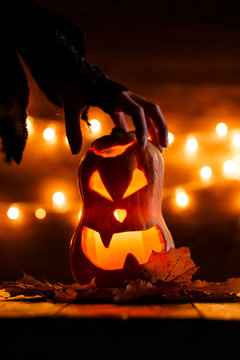 Photo of halloween pumpkin cut in shape of face with witch's hand
