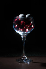 Wine glass filled with Christmas balls. On a black background.