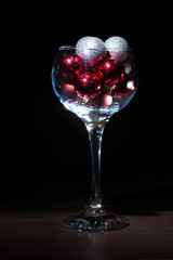 Wine glass filled with Christmas balls. On a black background.