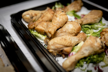 Close up of roast chicken drum sticks at a buffet on a tray with lettuce as a garnish