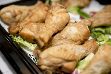 Close up of roast chicken drum sticks at a buffet on a tray with lettuce as a garnish