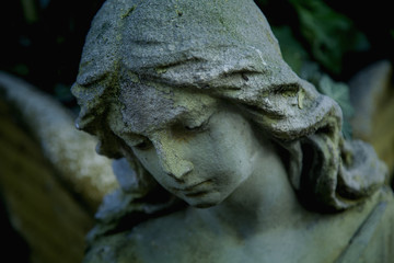 Vintage image of a sad angel on a cemetery against the background of leaves