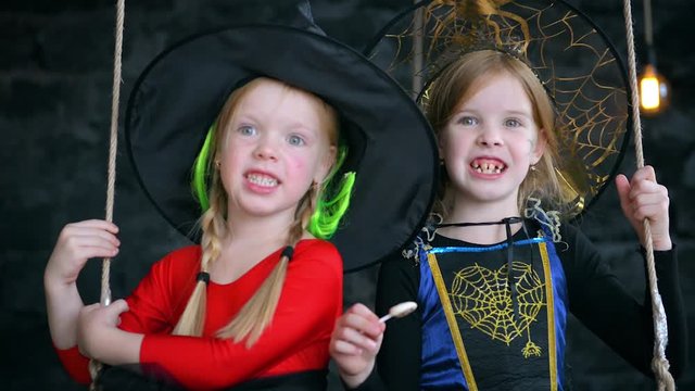 A little girls, a witches, ride on a swing on Halloween