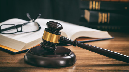 Judge gavel on a wooden desk, law books background