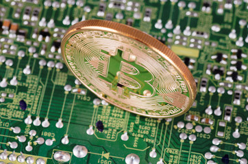 Golden plated bitcoin on a printed circuit board.