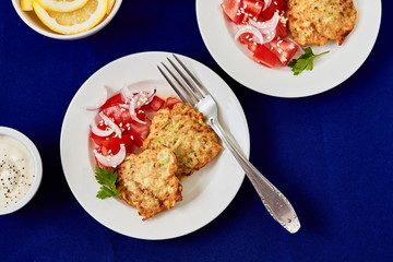 Healthy, vegetarian food. Zucchini pancakes.served with fresh tomato and red onion salad and yogurt sauce, top view