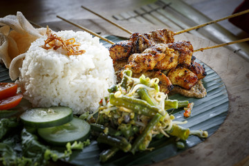 delicious chicken satay, indonesian grilled chicken skewers served on banana leaf