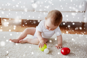 happy baby playing with balls on floor at home