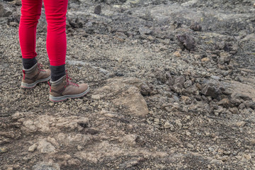 Girl standing on rocky ground with red trousers and  hiking boots 