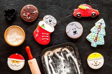 Gingerbread cookies for new year 2018 near rolling pin and flour on black background top view