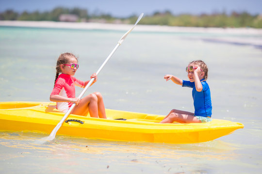 Little adorable girls enjoying kayaking on yellow kayak