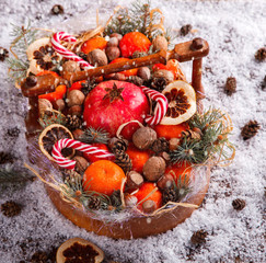 Fototapeta na wymiar Christmas New Year Composition with Tangerines Pine cones Walnuts,Hazelnuts and Candy Cane on wooden Vintage Tray.Holiday Card.Holiday Decoration to Russian Tradition.Drawn Snowfall.selective focus .