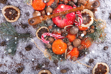 Christmas New Year Composition with Tangerines Pine cones Walnuts,Hazelnuts  and Candy Cane on wooden Vintage Tray.Holiday Card.Holiday Decoration to Russian Tradition.Drawn Snowfall.selective focus .