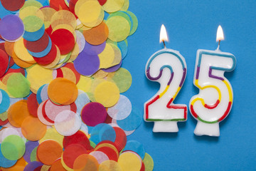 Number 25 celebration candle with party confetti