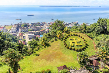 Sandakan town landscape with green lawn in Hindu counterclockwise swastika shape and blue Sulu sea...