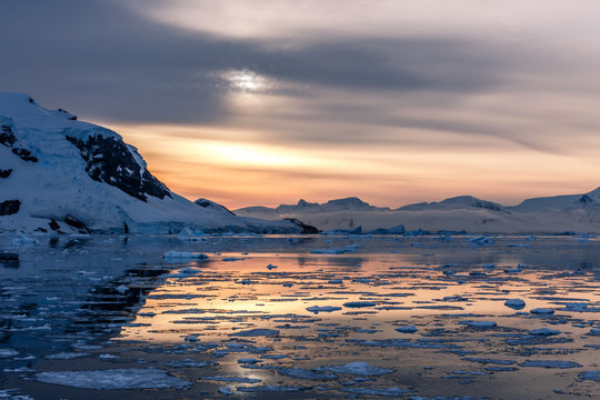 Sunset over idyllic lagoon with mountains and icebergs in the background at the Lemaire Strait, Antarctica