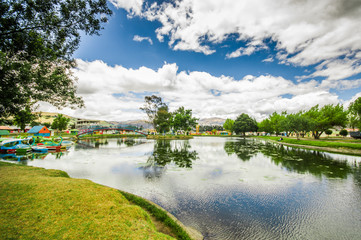 Fototapeta na wymiar Beautiful day of an artificial lake located in the midle of a park, with the reflection in the water, in the city of Cayambe, Ecuador