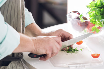 Obraz na płótnie Canvas A man chef shreds greens at a white table