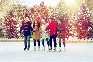 Naklejka premium happy friends ice skating on rink outdoors