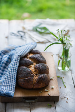 Plaited bread with poppy seed on a breadboard