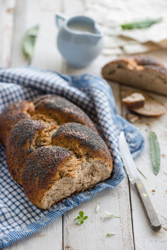 Plaited bread with poppy seed on a white table