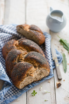 Plaited bread with poppy seed on a white table