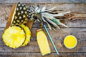 Freshly squeezed pineapple juice near fruit slices on wooden background top view