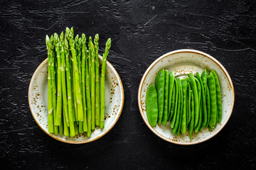Fresh asparagus on the plates on black background top view