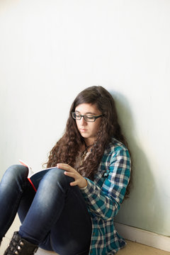 Young woman sitting on the floor and reading a book