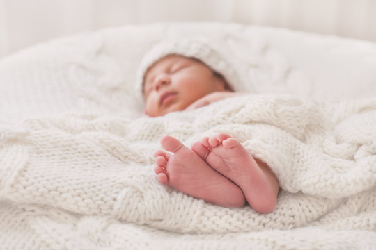 Sleeping newborn baby lying on a white blanket with his feet in focus