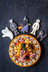 Halloween bakery and sweets. Pumpkin pie, gummy spiders, gingerbread cookies on black background top view copyspace