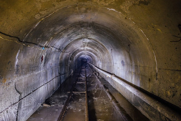 Abandoned flooded underground mine tunnel with pipe and narrow-gauge railway